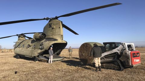 Nebraska Army National Guard soldiers load bales of hay into a CH-47 Chinook helicopter for airdrops to cattle stranded by flooding Wednesday in Columbus, Nebraska.