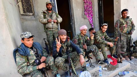 Fighters from the Syrian Democratic Forces returning from the frontline in Baghouz flash the "V" for victory sign.