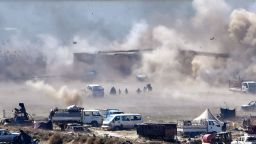 TOPSHOT - People are seen fleeing as heavy smoke rises above the Islamic State (IS) group's last remaining position in the village of Baghouz during battles with the Syrian Democratic Forces (SDF), in the countryside of the eastern Syrian province of Deir Ezzor on March 18, 2019. - A shroud of black smoke covered the Islamic State group's last Syria redoubt today as US-backed forces battled holdout jihadists after a night of shelling and heavy air strikes. The Kurdish-led SDF have been closing in on IS fighters holed up in a small sliver of territory in the village of Baghouz in eastern Syria since January. (Photo by GIUSEPPE CACACE / AFP)        (Photo credit should read GIUSEPPE CACACE/AFP/Getty Images)