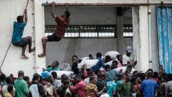 People take part in the looting sacks of Chinese rice printed "China Aid" from a warehouse which is surrounded by water after cyclone hit in Beira, Mozambique, on March 20, 2019. - Five days after tropical cyclone Idai cut a swathe through Mozambique, Zimbabwe and Malawi, the confirmed death toll stood at more than 300 and hundreds of thousands of lives were at risk, officials said. (Photo by Yasuyoshi CHIBA / AFP)        (Photo credit should read YASUYOSHI CHIBA/AFP/Getty Images)