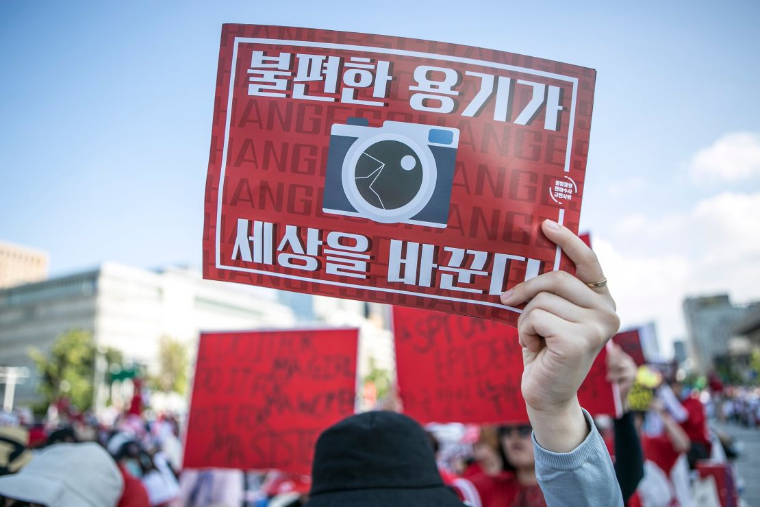 A woman holds up an anti-spy cam poster during a protest in Seoul in 2018. 