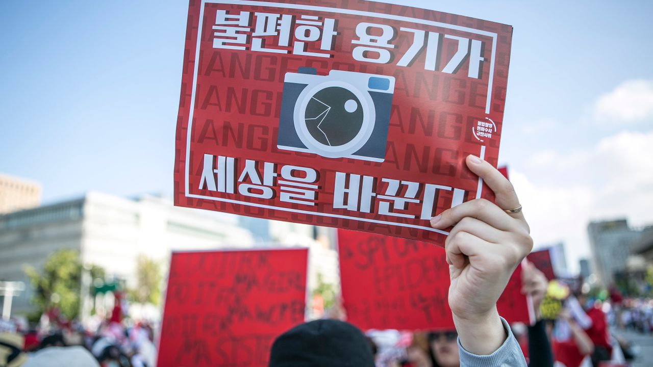 A woman holds up an anti-spy cam poster during a protest in Seoul in 2018. 