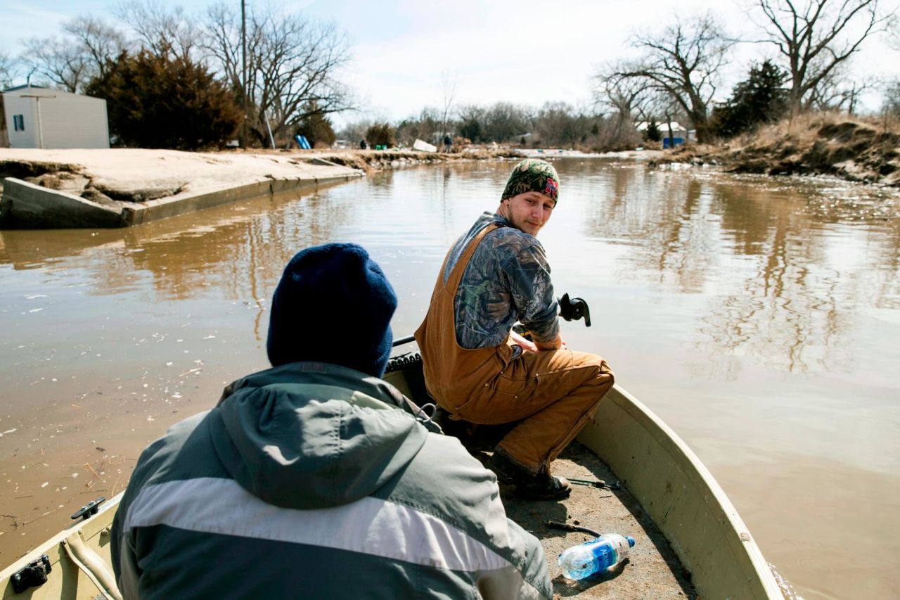 Helmut Shea Kaukver III watches from a boat alongside Tim Rockford in Bellwood, Nebraska, on Monday, March 18. Their neighborhood was only accessible by boat due to flooding.