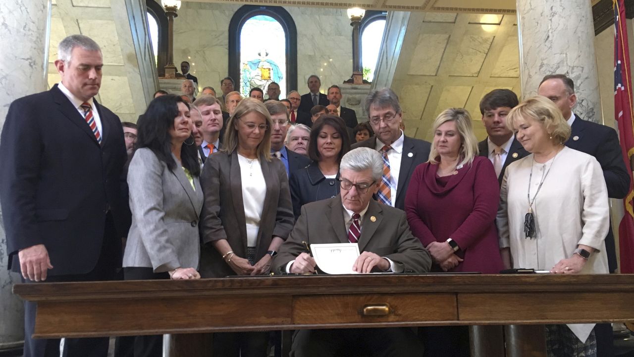 Mississippi Gov. Phil Bryant is surrounded by lawmakers as he signs a bill that would ban most abortions once a fetal heartbeat can be detected.