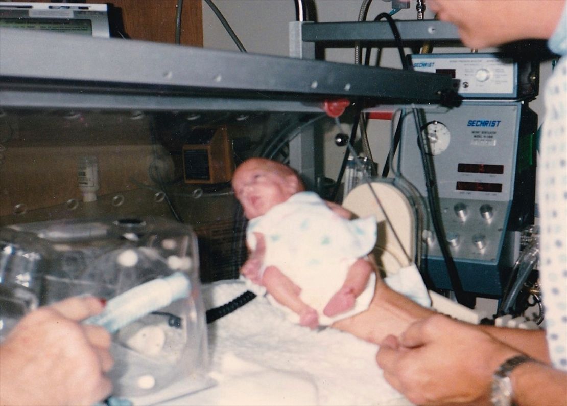 Lewis' father holds her in the NICU.