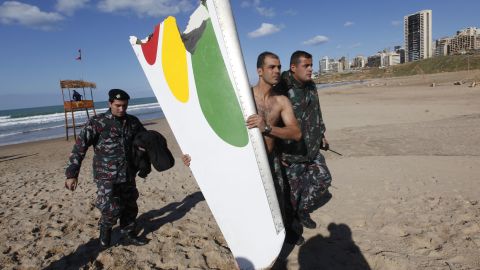 A firefighter carrying a part of the Ethiopian Airlines Boeing 737 that crashed in Lebanon in 2010.