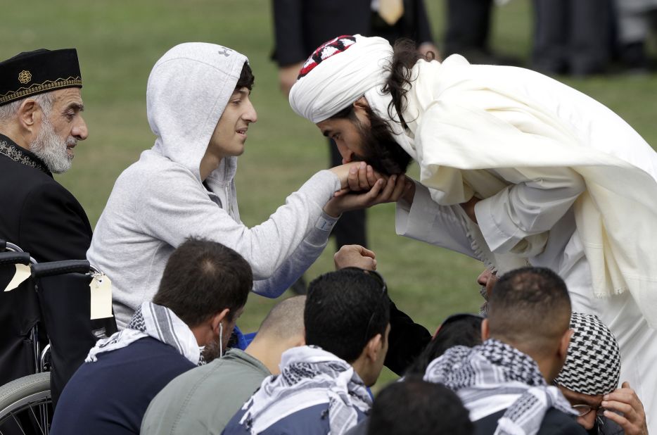 Zaid Mustafa, second left, son and brother of victims from the mosque attacks, is welcomed at Friday prayers at Hagley Park in Christchurch on March 22.