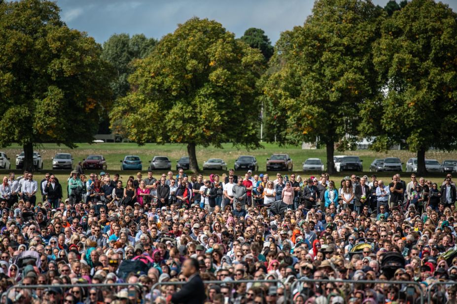 Visitors look on as Muslims attend Friday prayers in a park near Al Noor mosque in Christchurch, New Zealand.