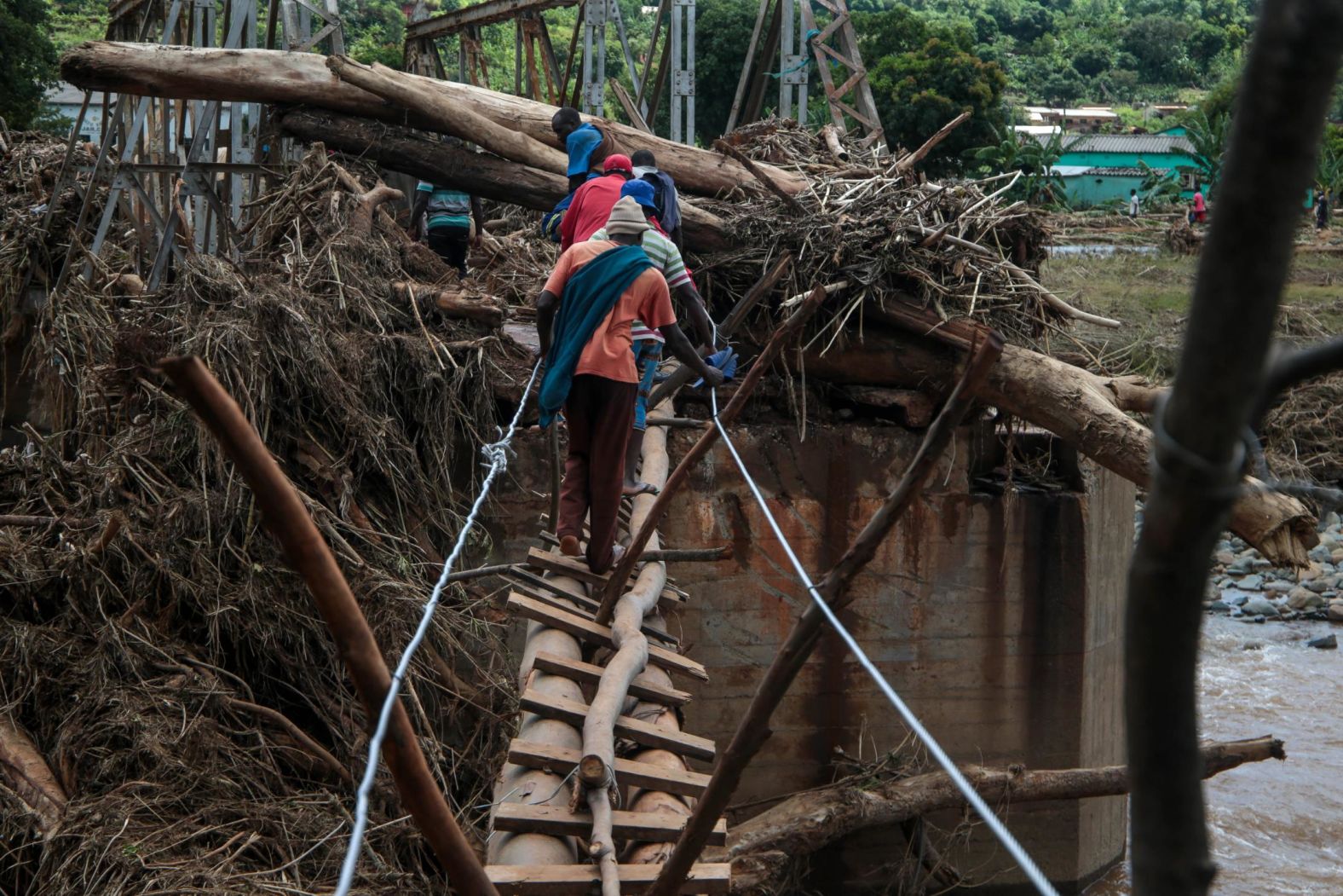 People cross a makeshift bridge over a river on Wednesday, March 20, that surged days earlier during Cyclone Idai in Chipinge, Zimbabwe.