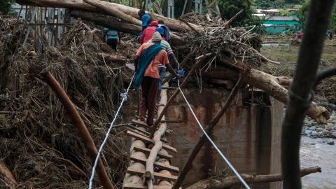 People cross a makeshift bridge over a river on Wednesday, March 20, that surged days earlier during Cyclone Idai in Chipinge, Zimbabwe.
