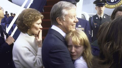Before departing for Georgia following Reagan's inauguration, Carter holds his crying daughter as his wife blows a kiss at Andrews Air Force Base in Maryland.