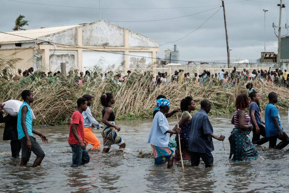 People carry Chinese rice from a warehouse surrounded by water after Cyclone Idai hit the area, in Beira, Mozambique.