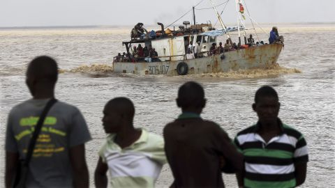 Men watch the arrival of a boat carrying displaced families rescued from a flooded area of Mozambique's Buzi district on March 23.