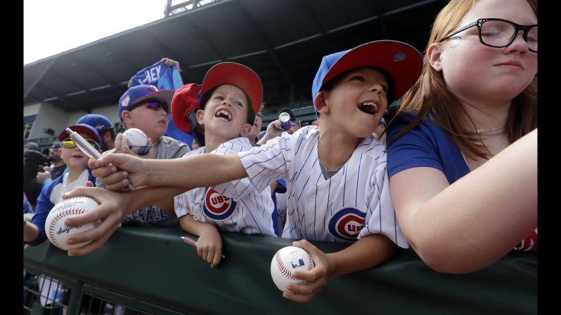 Reed Tomey, 6, center right, pushes away the arm of his brother, Rhett, 8, as the two attempt to get autographs from Chicago Cubs players before a spring training game against the Seattle Mariners in Mesa, Arizona, on Tuesday, March 19.