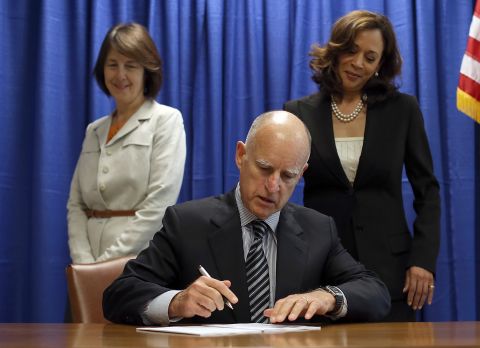 Harris watches California Gov. Jerry Brown sign copies of the California Homeowner Bill of Rights in July 2012.