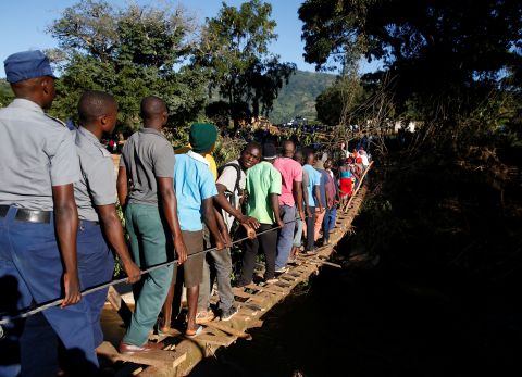 Survivors of the cyclone cross a temporary foot bridge to receive aid in Chipinge, Zimbabwe, on March 25.