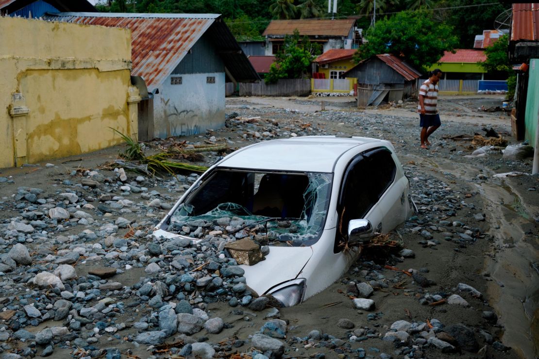 A car sits abandoned in the mud on a flooded street.