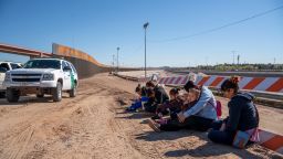 Salvadoran migrants wait for a transport to arrive after turning themselves into US Border Patrol by border fence under construction in El Paso, Texas on March 19, 2019. 