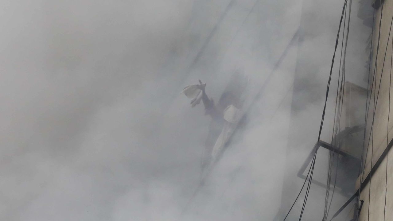 A trapped person signals to be rescued from the building.