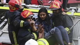 Bangladeshi firefighters rescue a woman from a burning office building in Dhaka on March 28, 2019. - A huge fire tore through a Dhaka office block March 28 killing at least five people with many others feared trapped in the latest major inferno to hit the Bangladesh capital. (Photo by MUNIR UZ ZAMAN / AFP)        (Photo credit should read MUNIR UZ ZAMAN/AFP/Getty Images)