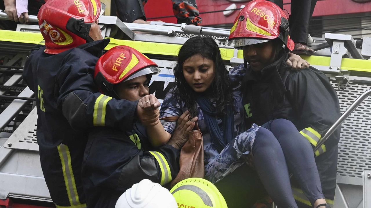 Firefighters carry a woman rescued from the building.