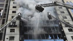 Bangladeshi firefighters on ladders work to extinguish a blaze in an office building in Dhaka on March 28, 2019. - A huge fire tore through a Dhaka office block March 28 killing at least five people with many others feared trapped in the latest major inferno to hit the Bangladesh capital. (Photo by MUNIR UZ ZAMAN / AFP)        (Photo credit should read MUNIR UZ ZAMAN/AFP/Getty Images)
