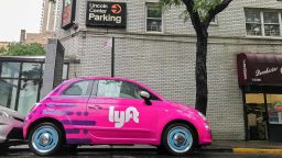 Fiat 500 painted pink and carrying a Lyft logo is parked in the streets of Manhattan.