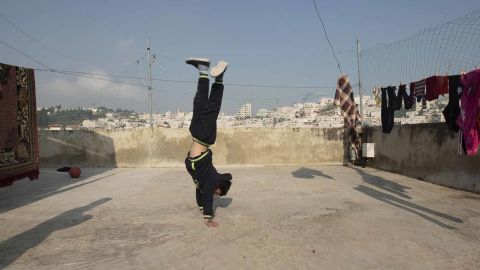 Zein Idris plays on the rooftop of his house in Hebron.