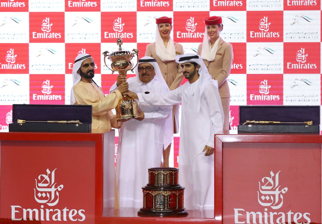 Sheikh Mohammed (L), receives the trophy after his horse Thunder Snow's victory at the Dubai World Cup.