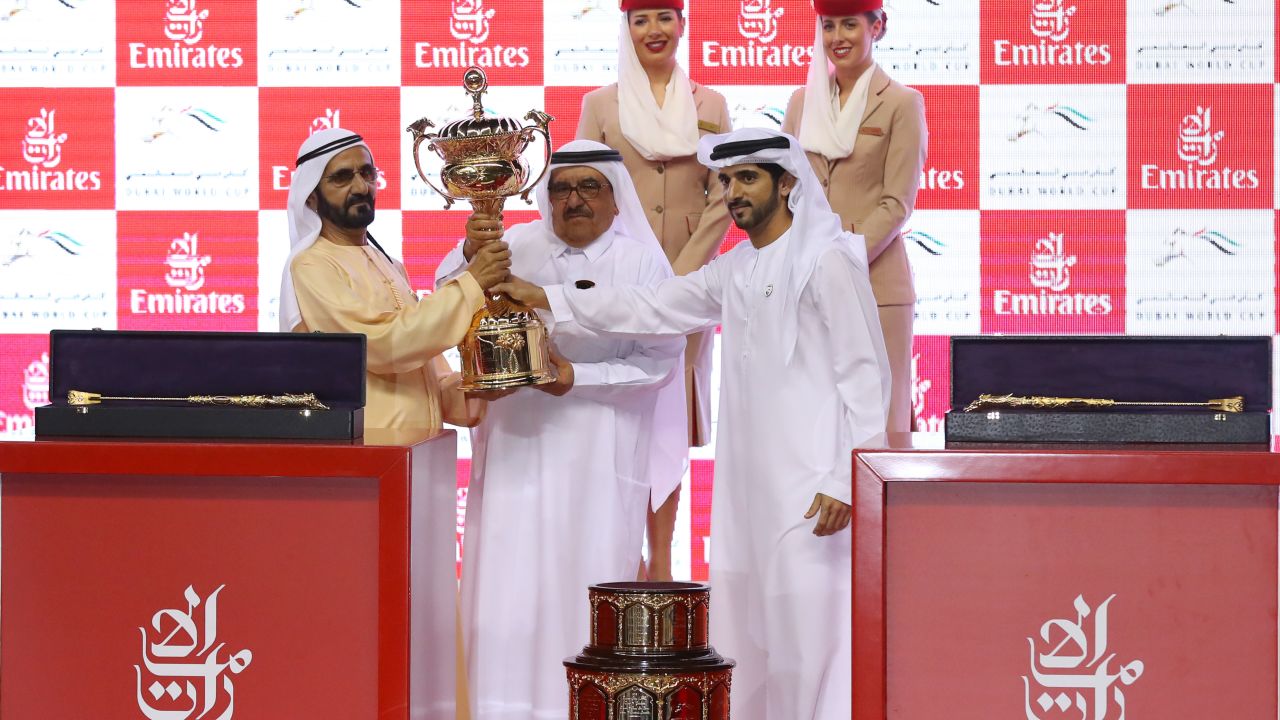 Sheikh Mohammed (L), receives the trophy after his horse Thunder Snow's victory at the Dubai World Cup.