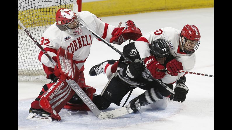 Providence's Tyce Thompson (27) falls to the ice with Cornell's Brendan Smith (27) in front of Cornell goalie Austin McGrath (32) during the second period of the NCAA Division I East Regional final men's hockey game in Providence, Rhode Island, on Sunday, March 31.