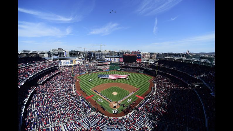Members of the New York Mets and the Washington Nationals line the baselines as they listen to the playing of the national anthem on Opening Day at Nationals Park on March 28 in Washington, DC.
