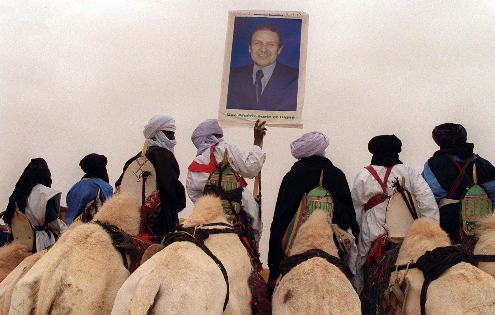 Bouteflika supporters ride camels and hold up a poster of the presidential candidate in April 1999.