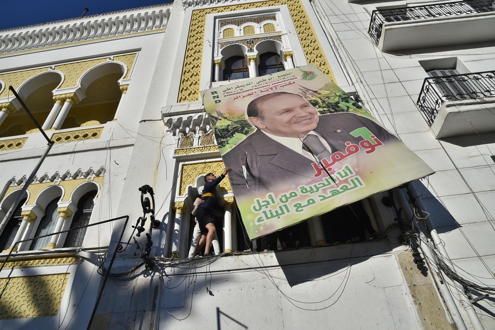 Demonstrators, protesting against Bouteflika's candidacy, tear down a large billboard of him in Algiers in February 2019.