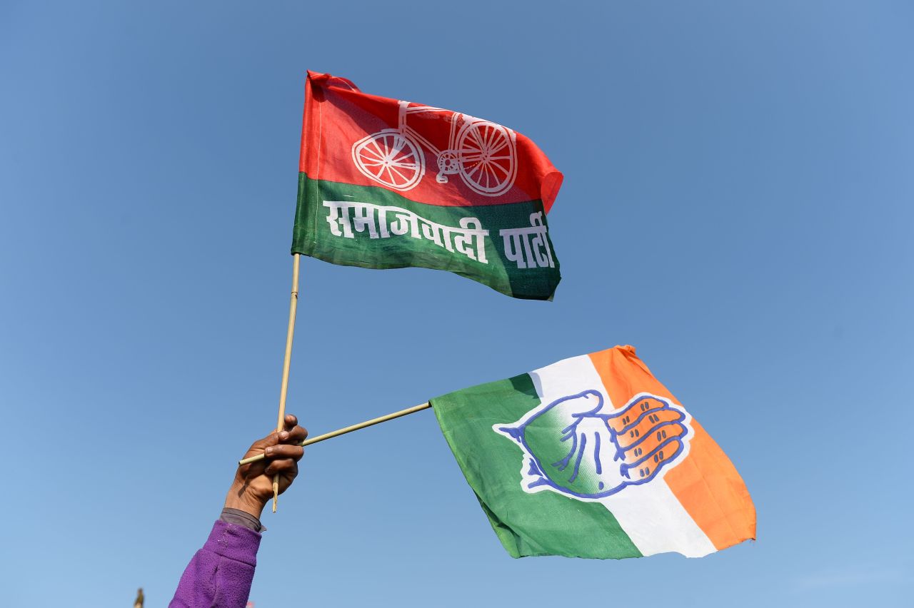A flag shows the open-palmed hand symbol of the Indian National Congress, alongside the bicycle symbol of the Samajwadi Party.