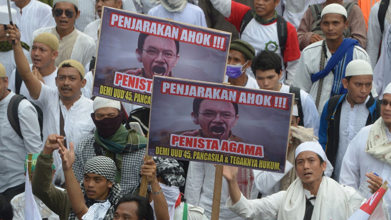 Indonesian Muslim demonstrators, holding banners that read "put Ahok in jail," march towards the presidential palace in Jakarta on November 4, 2016.