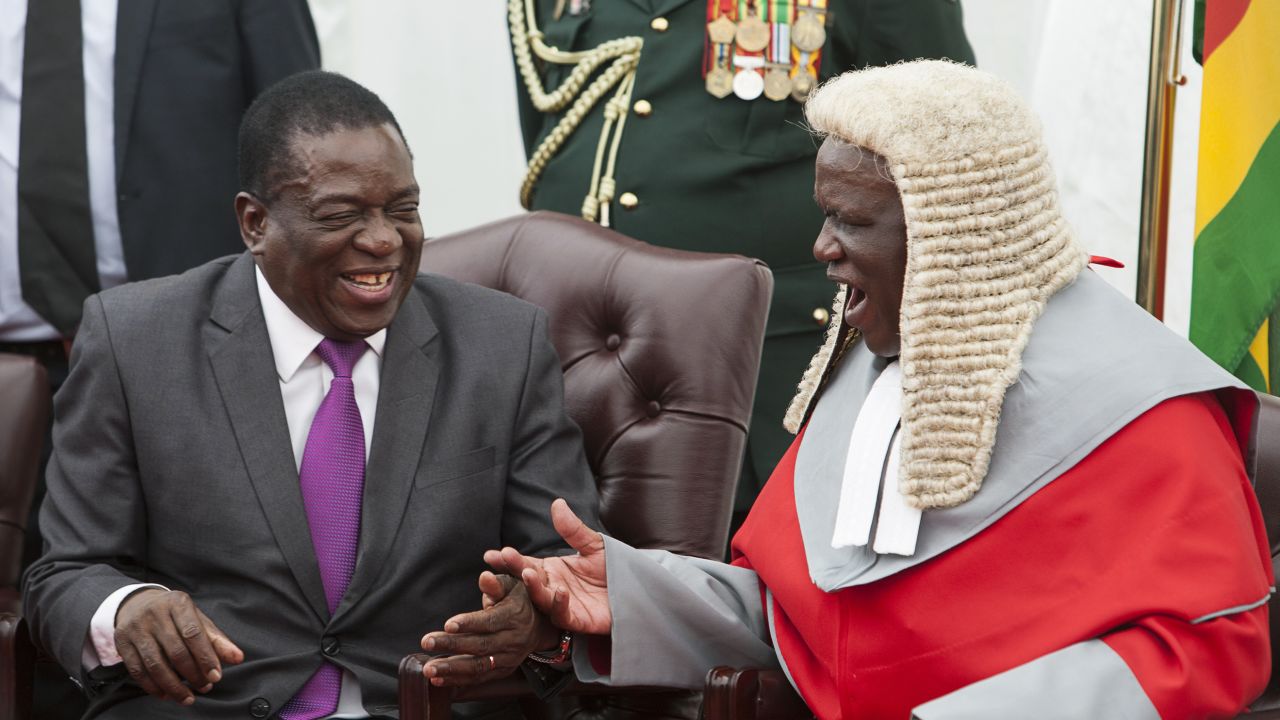 Zimbabwe's President Emmerson Mnangagwa, left, shakes hands with the country's chief justice Luke Malaba.