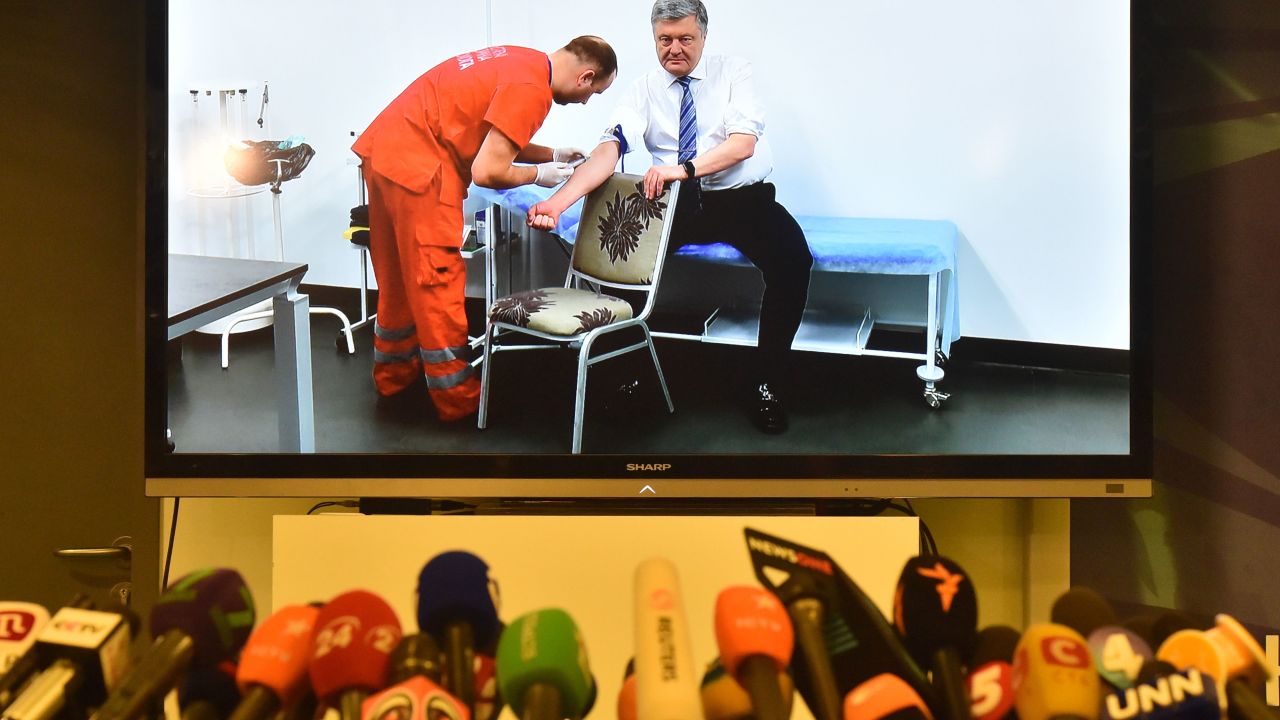 Microphones in front of a screen showing Ukrainian President Petro Poroshenko undergo a blood test live.