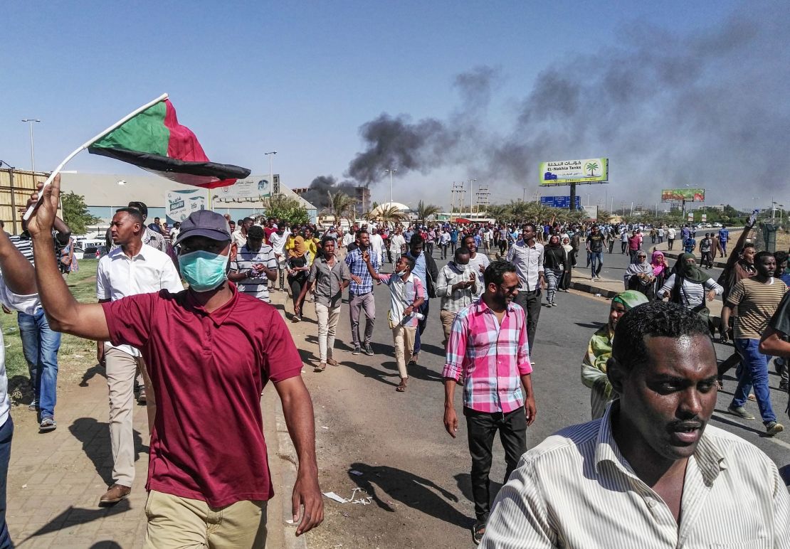 Sudanese protesters waive the national flag as they march toward the army headquarters.