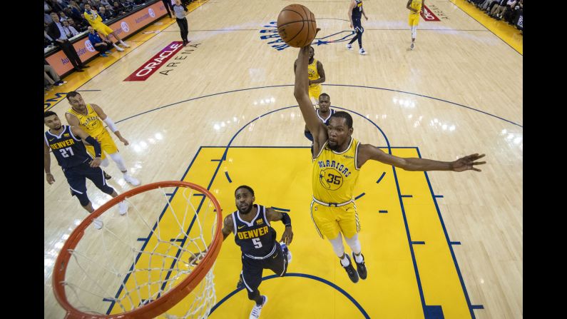 Golden State Warriors forward Kevin Durant dunks while defended by Denver Nuggets guard Will Barton during the first half of their NBA game at Oracle Arena in Oakland on April 2.