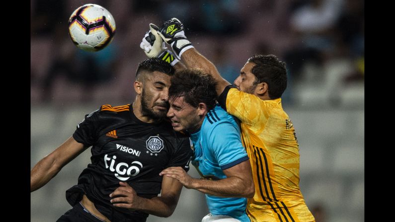 Olimpia player Maximiliano Olivera collides with Omar Merlo and goalkeeper Patricio Alvarez of Sporting Cristal during a Libertadores Cup soccer match at the National stadium in Lima, Peru, on April 4.
