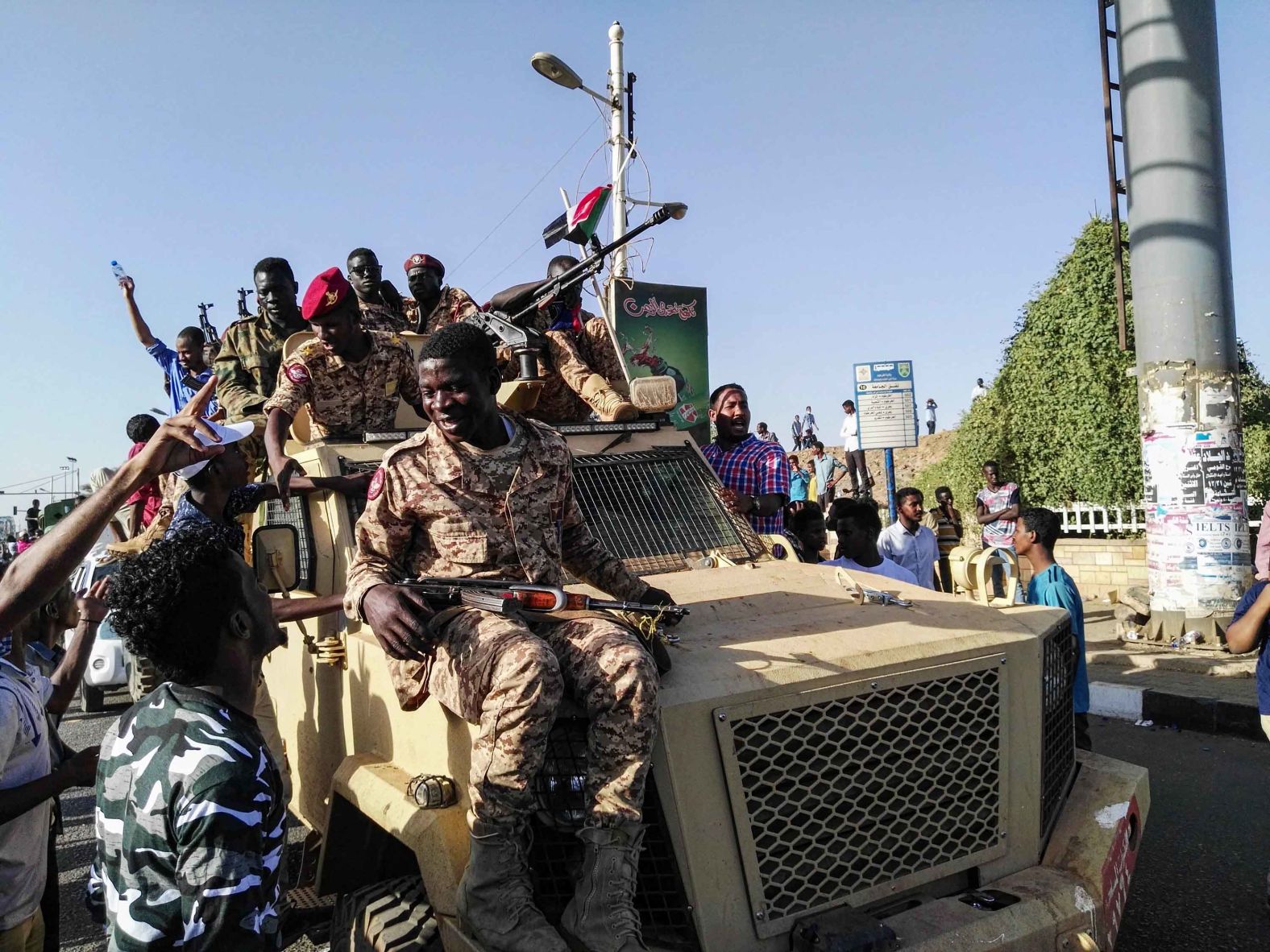 Protesters sit atop a military vehicle as soldiers stand nearby on April 7.