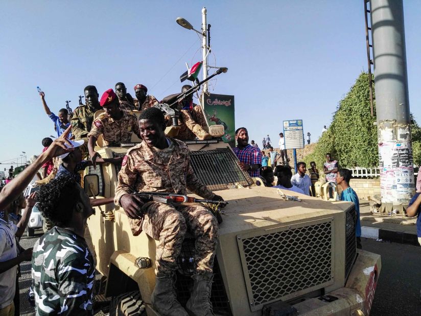 Protesters sit atop a military vehicle as soldiers stand nearby on April 7.
