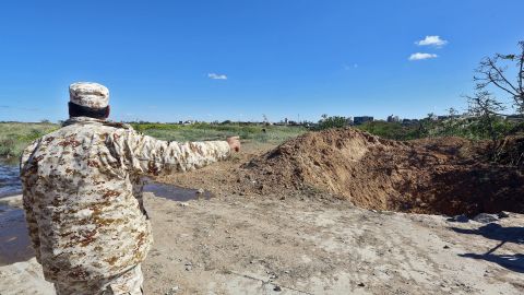 A member of the Libyan security forces points towards a crater on the ground following an air strike at Mitiga International Airport in the capital Tripoli on April 8, 2019.