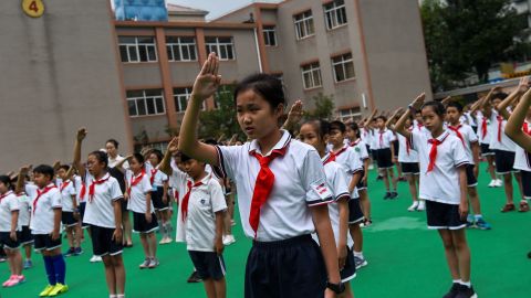 In this 2017 photograph, students sing the national anthem on the playground during the flag-hoisting ceremony at their school in Shanghai, China.