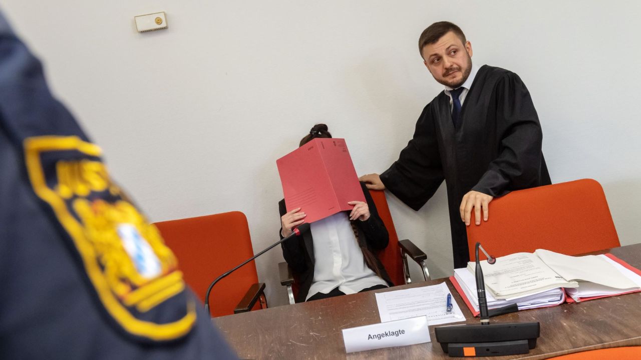 Defendant Jennifer W. hides her face behind a folder while sitting next to her lawyer Ali Aydin in court in Munich, southern Germany, on April 9, 2019. 