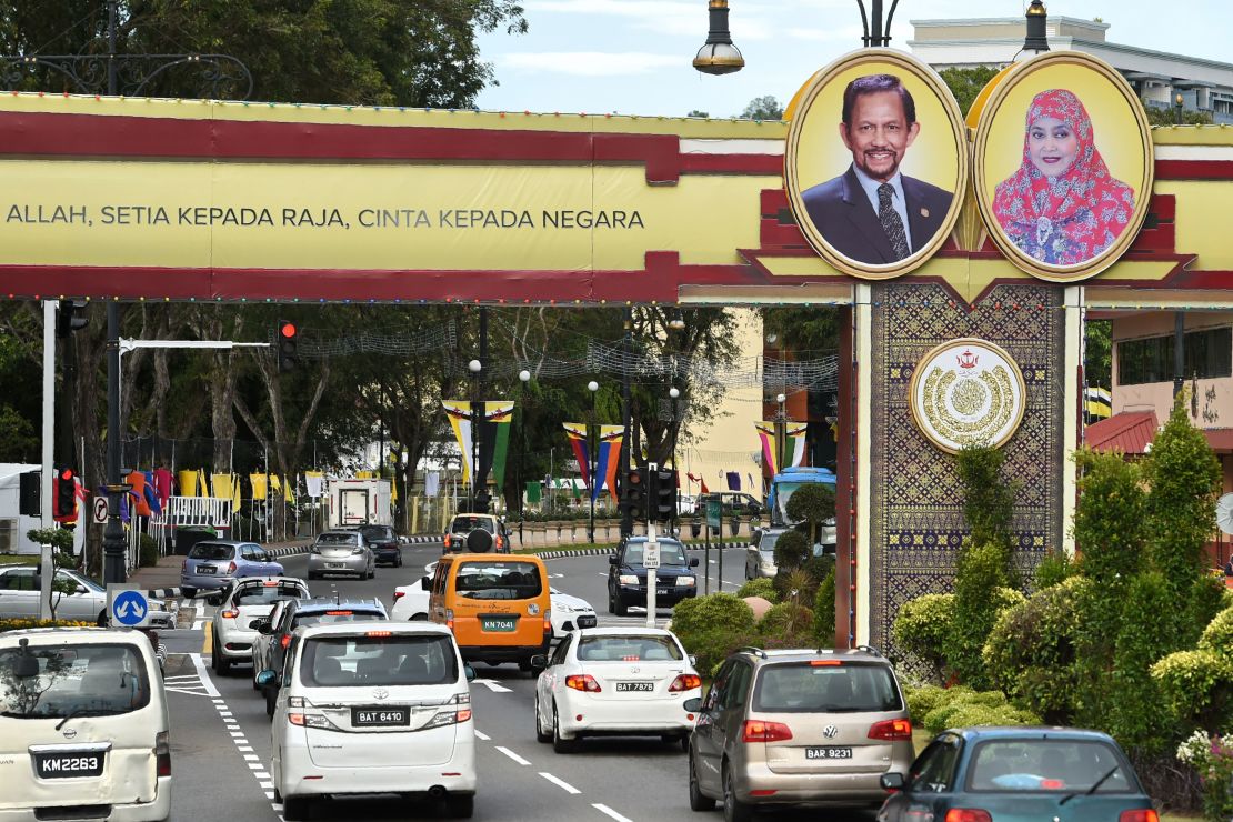 Portraits of Brunei's Sultan Hassanal Bolkiah and Queen Saleha are seen beside a slogan (partially cutoff) in Bahasa Melayu that reads "Obedience to Allah, loyalty to the king, love for the country" in Bandar Seri Begawan on October 4, 2017. 
