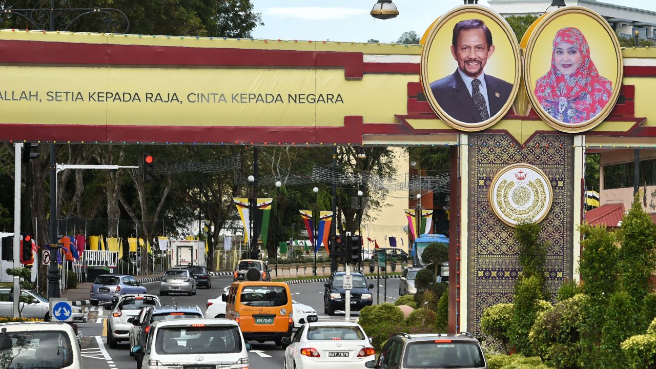 Portraits of Brunei's Sultan Hassanal Bolkiah and Queen Saleha are seen beside a slogan (partially cutoff) in Bahasa Melayu that reads "Obedience to Allah, loyalty to the king, love for the country" in Bandar Seri Begawan on October 4, 2017. 

