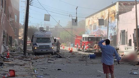 A witness from a building across the street said, "Half the block is destroyed." CNN has blurred a figure at center left due to a graphic injury.
