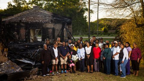 Members of the congregation of Greater Union Baptist Church stand for a portrait in front of the ruins of their former church.